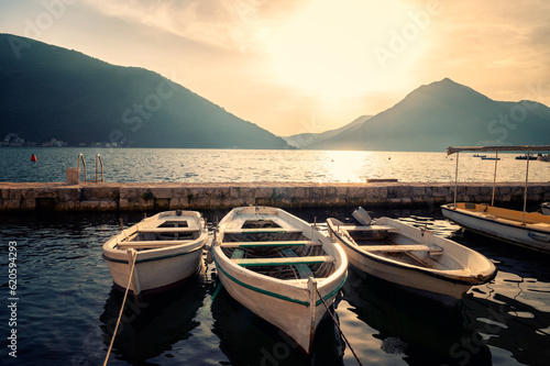 Panoramic view from the promenade of the picturesque town of Perast in the Bay of Kotor with boats on the piers at sunset, Montenegro.