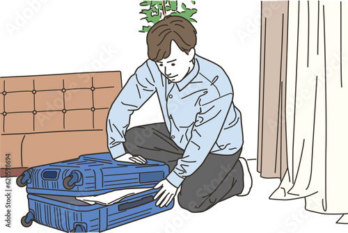 スーツケースの前で荷造りをする若い男性