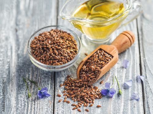 Flax seeds and flax oil. Brown linen seeds and flaxseed oil on old gray wooden background. Copy space