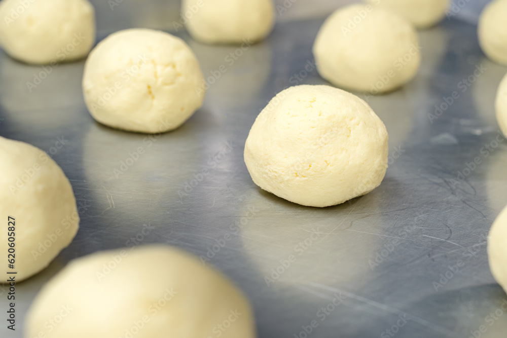 Raw almojabanas on a baking sheet. Small rolls made with milk, cheese and flour, typical of Colombian gastronomy, on an aluminum can in the production area of a bakery. Raw almojabanas on a baking sheet. Small rolls made with milk, cheese and flour, typical of Colombian gastronomy, on an aluminum can in the production area of a bakery.