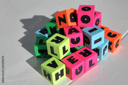 Colorful letter cubes in natural sunlight. Strong shade or shadow. White background.