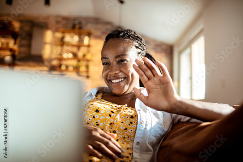 Foto Young woman using a laptop while sitting on the couch in the living room