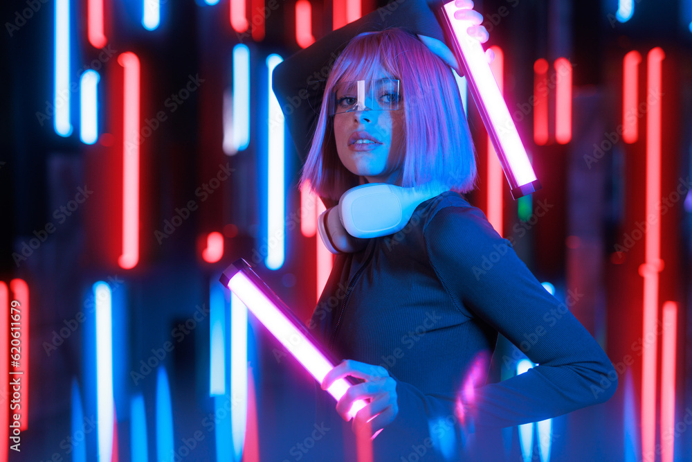 Woman in futuristic costume. Girl in glasses of virtual reality while touching air. Augmented reality game, future technology, AI concept. VR. Neon blue and red light. Dark background. Woman in futuristic costume. Girl in glasses of virtual reality while touching air. Augmented reality game, future technology, AI concept. VR. Neon blue and red light. Dark background.