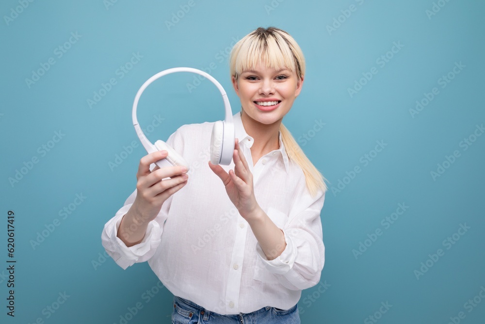 portrait of a stylish young pretty blond secretary woman dressed in a white blouse listening to music through wireless bluetooth headphones. business concept portrait of a stylish young pretty blond secretary woman dressed in a white blouse listening to music through wireless bluetooth headphones. business concept