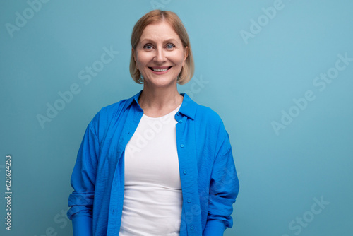 smiling mature woman thinking brilliant idea on blue background with copyspace