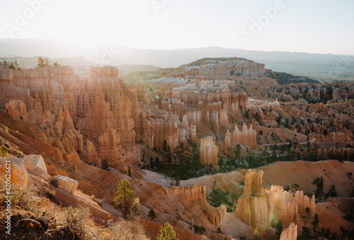 Bryce Canyon at first light, view from rim trail at Sunrise Point into canyon, contre-jour shot into sun with lens flares and copy space