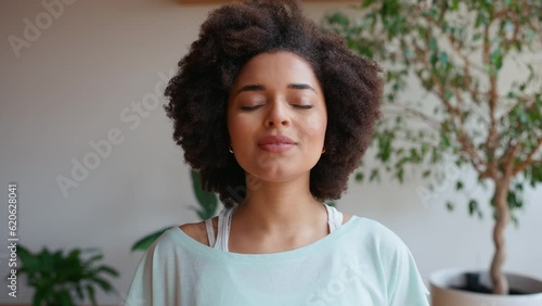 Handsome african curly haired woman breathing and looking at camera at home. Healthy lifestyle. Sport