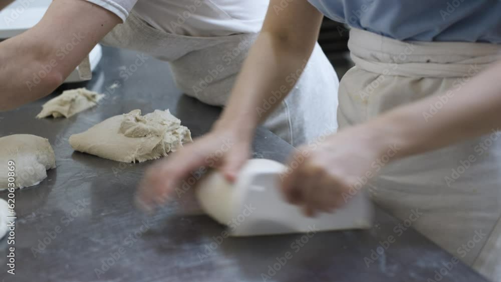 The female hands of the bakery workers separate portions of the dough to be weighed on the scales for making bread. Craft bakery. Production of tasty and healthy bread The female hands of the bakery workers separate portions of the dough to be weighed on the scales for making bread. Craft bakery. Production of tasty and healthy bread