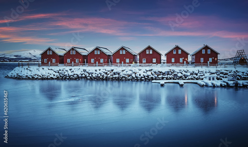 Classic red fishing cottages in perfect symmetry sitting along a stone jetty with a slightly blurred reflection during sunset. Travel, adventure and freedom concept. popular travel destinations.