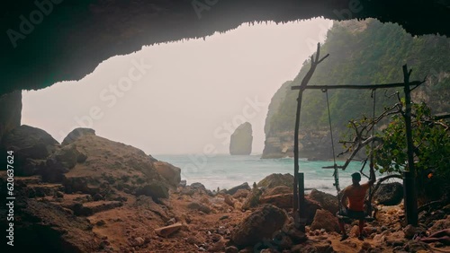 ctive lifestyle travel people enjoy beautiful view from mountain cave on foggy landscape coastline tropical beach Bali with scenery cliff in ocean in Tembeling Beach and forest Bali, Indonesia photo