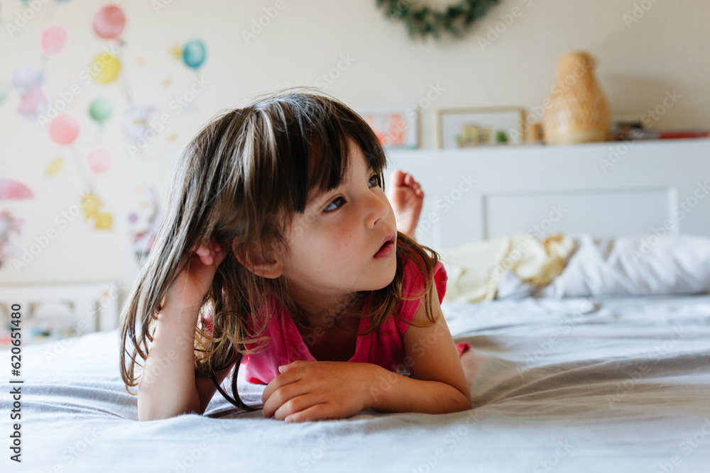 thoughtful small girl lying on the parents bed thoughtful small girl lying on the parents bed