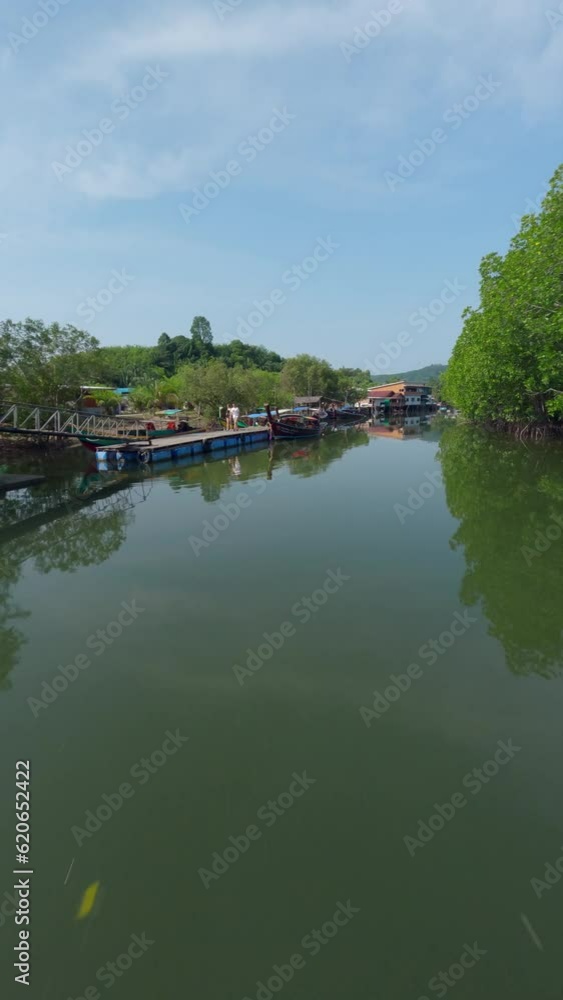 Vertical video 4k. Low dynamic flying over Asian village boat water river local rural house green forest aerial view. FPV sport drone close low shot tropical countryside port harbor fishing ship sunny Vertical video 4k. Low dynamic flying over Asian village boat water river local rural house green forest aerial view. FPV sport drone close low shot tropical countryside port harbor fishing ship sunny