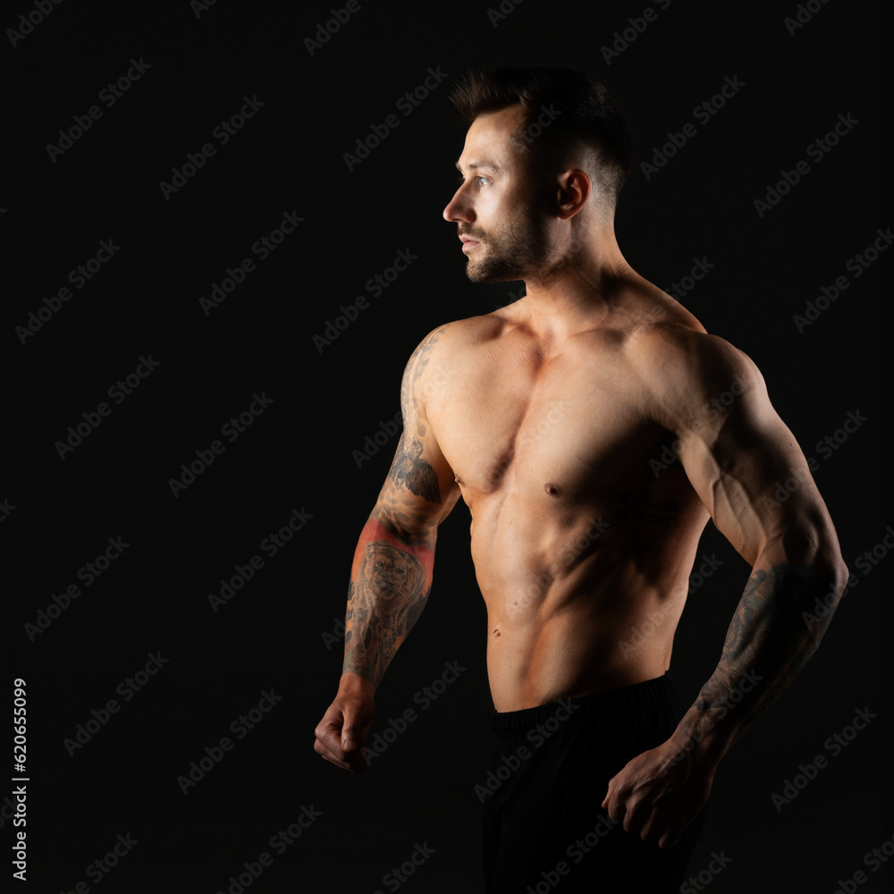 Fototapeta premium Man with bare muscular torso, studio photo on black background. Bodybuilder.