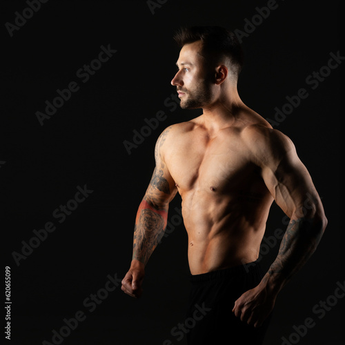 Man with bare muscular torso, studio photo on black background. Bodybuilder.