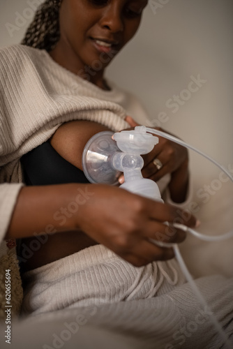 Smiling female using machine for pumping breastmilk
