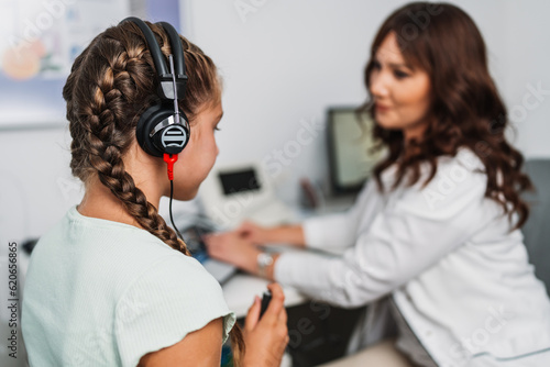 Audiologist doing impedance audiometry or diagnosis of hearing impairment. An beautiful teenage girl getting an auditory test at a hearing clinic. Healthcare and medicine concept. photo