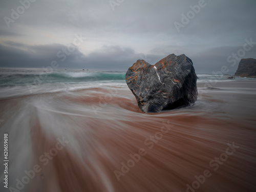 Long exposure of the flowing sea and a heart shaped rock on the Portizuelo beach, Asturias, Spain photo