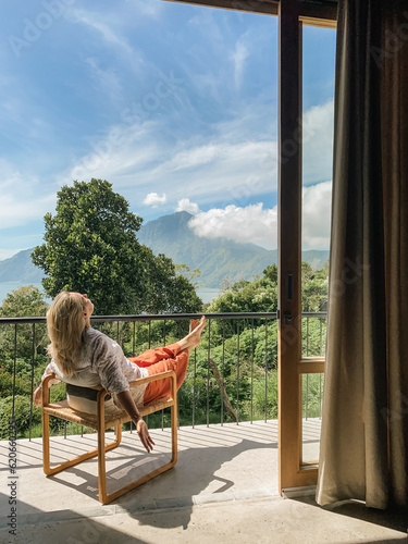 Woman relaxing in a chair on a balcony with mountain views