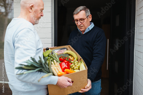 Caregiver delivering food at door of senior man photo