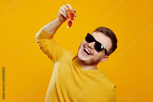 Fototapeta Close up photo of excited man with sunglasses holding and trying to bite slice o