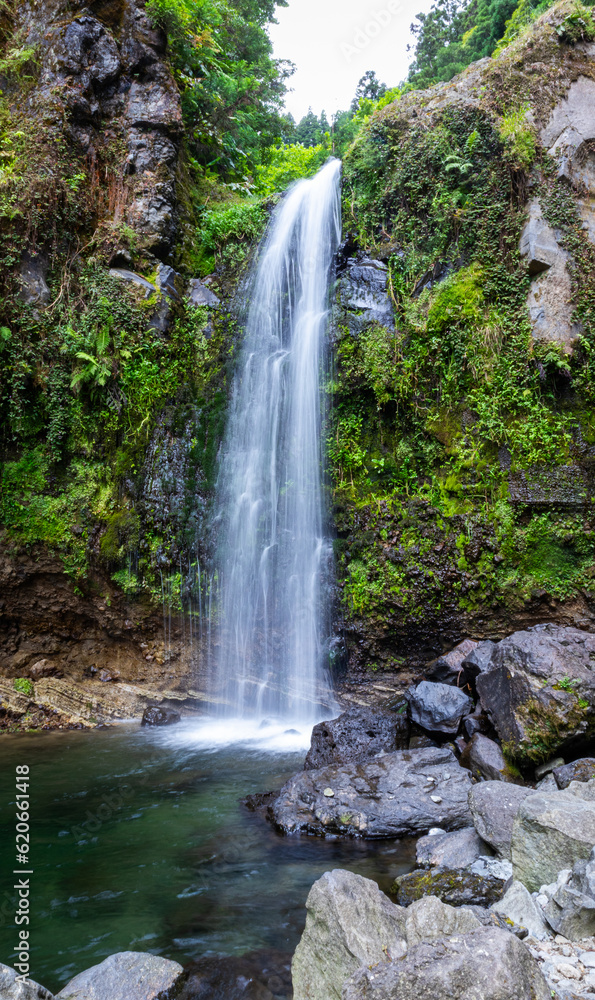 Obraz premium Beautiful waterfall in the middle of the rocks and nature with a defuminated effect in Salto do Cabrito, Azores