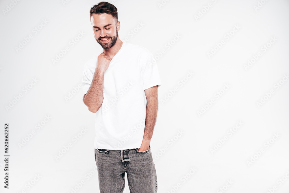 Portrait of handsome smiling stylish hipster lambersexual model. Sexy man dressed in white T-shirt and jeans. Fashion male isolated on white background in studio Portrait of handsome smiling stylish hipster lambersexual model. Sexy man dressed in white T-shirt and jeans. Fashion male isolated on white background in studio