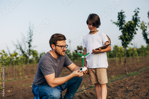 Caucasian man and his son play with a windmill model outdoors. © cherryandbees