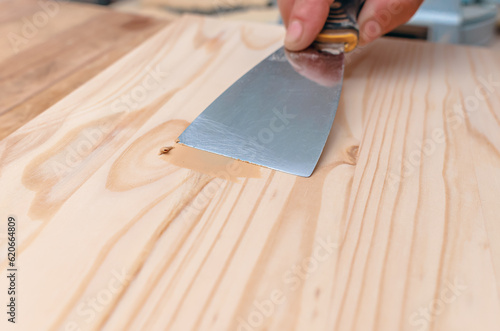 The process of puttying a wooden board. Spatula, putty, wooden board. Carpentry works.