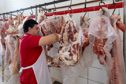 Butcher processing animal carcass suspended by the hooks photo