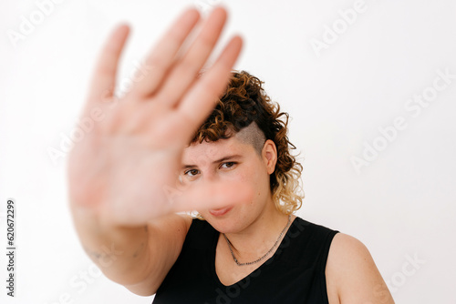Positive queer showing stop gesture with palm of hand photo