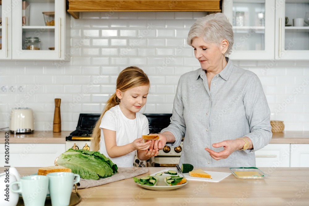 Senior woman and kid cooking sandwiches in kitchen Senior woman and kid cooking sandwiches in kitchen