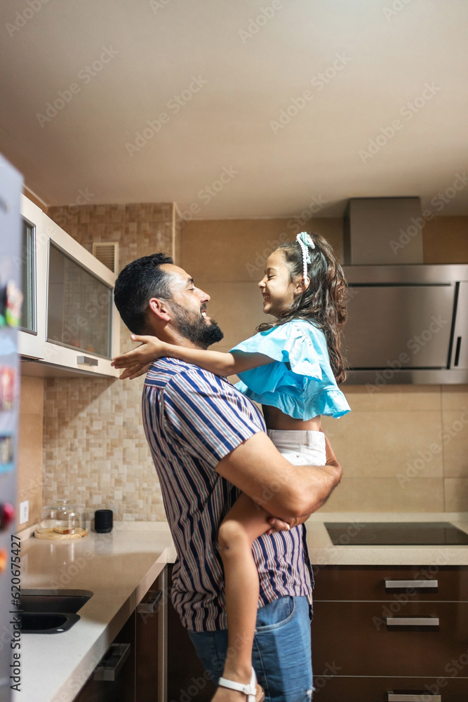 Father with little daughter in the kitchen at home hugging Father with little daughter in the kitchen at home hugging