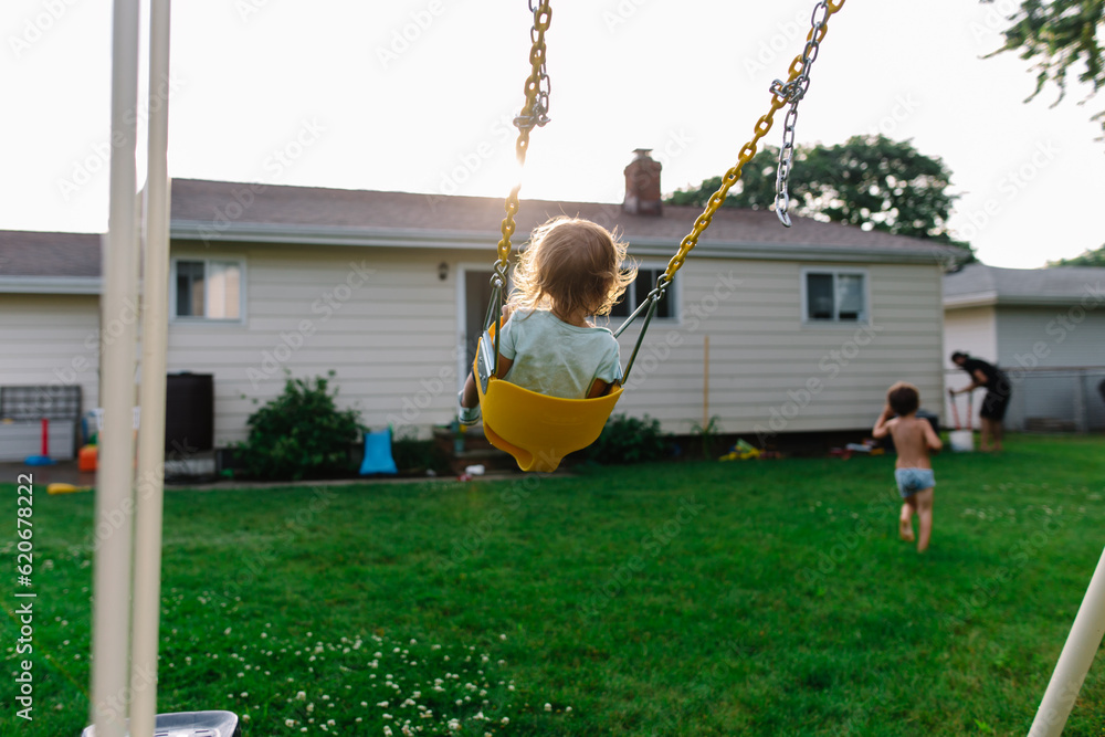Sister swings on play set while brother runs away Stock Photo | Adobe Stock