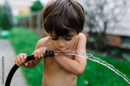 Boy drinks water from hose