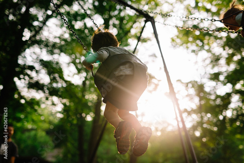 Child swinging on swing in woody area photo