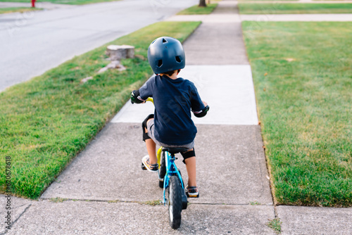 Young boy rides bike down sidewalk photo