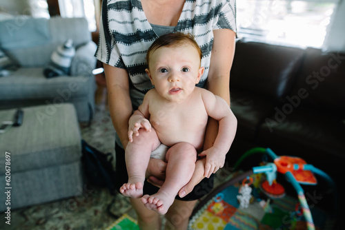 Focus on baby sitting in mother's arms at home photo