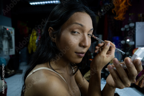 A hai transgender aritst finishes her eye makeup before a show photo