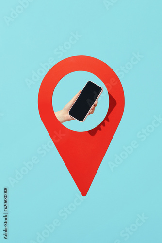 A hand holds a smartphone in location pin