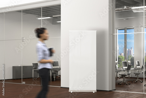 Blank roll up banner stand in office interior. 3d illustration