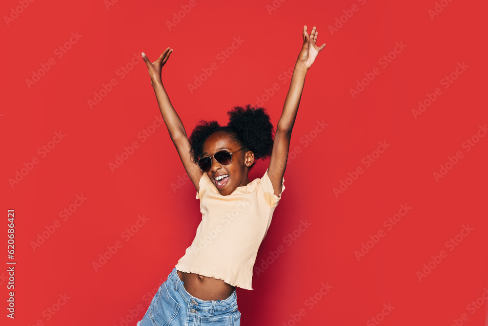 Excited black girl with raised arms on red background Stock Photo ...