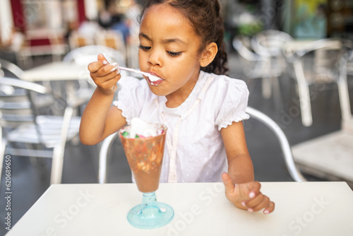 small girl eating ice cream enthusiastically outdoors