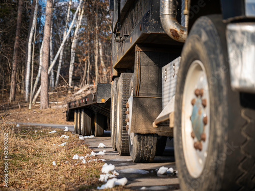 Tires and wheels and right side of a truck and trailer on paved road.