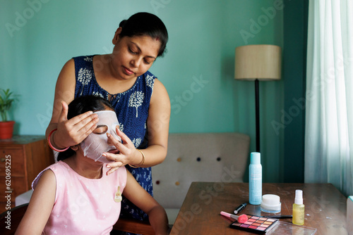 Mother applying facemask to her daughters face for skincare photo