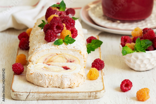 Obraz na płótnie Meringue roll with butter cream and raspberry curd, decorated with berries on a light background. w salonie