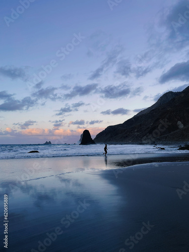 Man dark silloutte running on Benijo beach in Tenerife during sunset photo