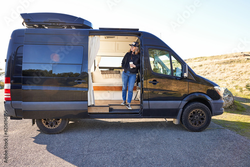 Portrait of woman with coffee in camper van in nature photo