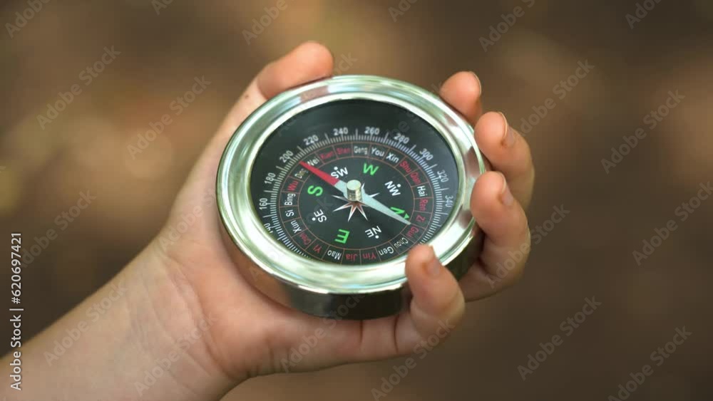 Compass in hand close up in green forest Compass in hand close up in green forest