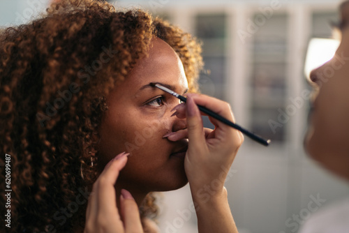 Woman having her eyebrows done by a makeup artist photo