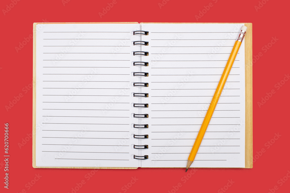 An open notebook with a binding and a yellow pencil on a red background. Open notepad with blank sheets in top view. Free space for text. Blank notebook pages ready to be used in design An open notebook with a binding and a yellow pencil on a red background. Open notepad with blank sheets in top view. Free space for text. Blank notebook pages ready to be used in design